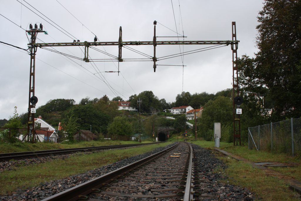Tågräls som går mot en tunnel. Framför tunneln fins det röda ljus som påminner om stopljus.